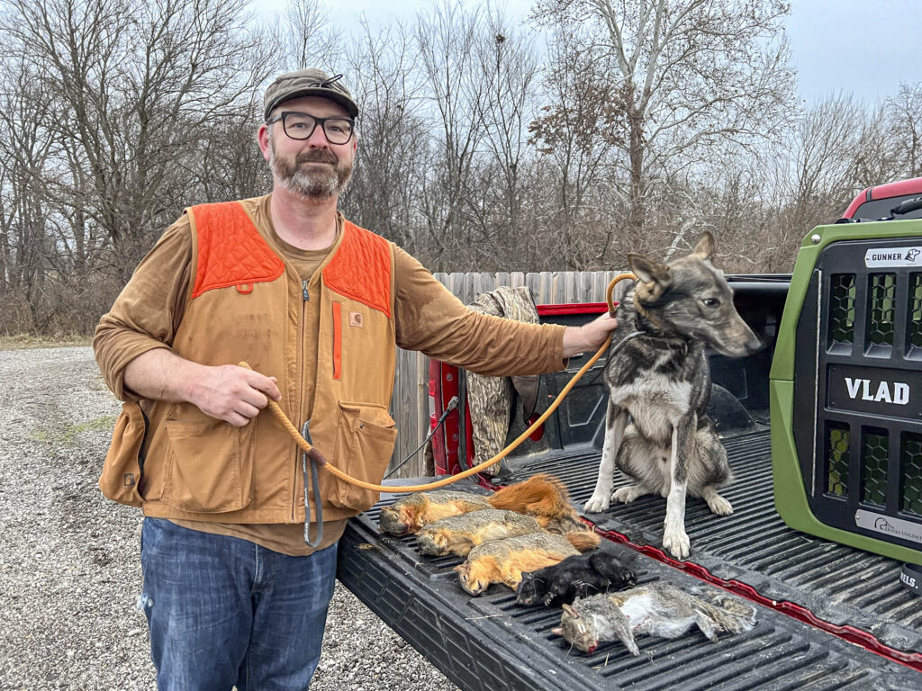 A squirrel hunter on the tailgate of his truck with a West Siberian Laika and dead squirrels.