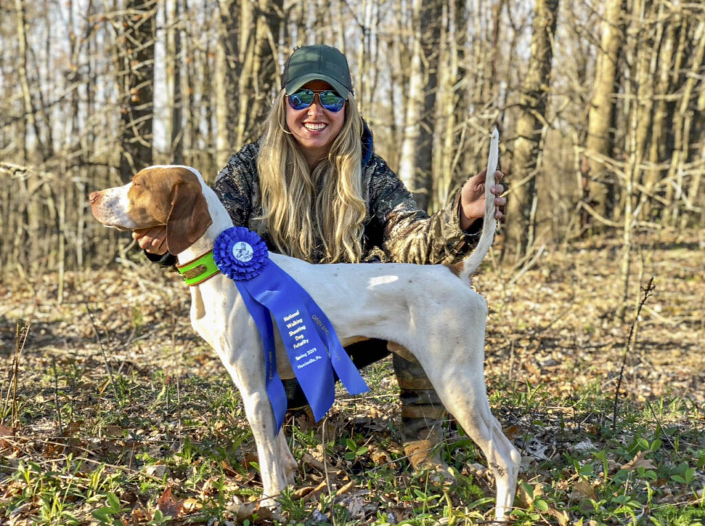 A female handler with her English pointer after winning a bird dog field trial.