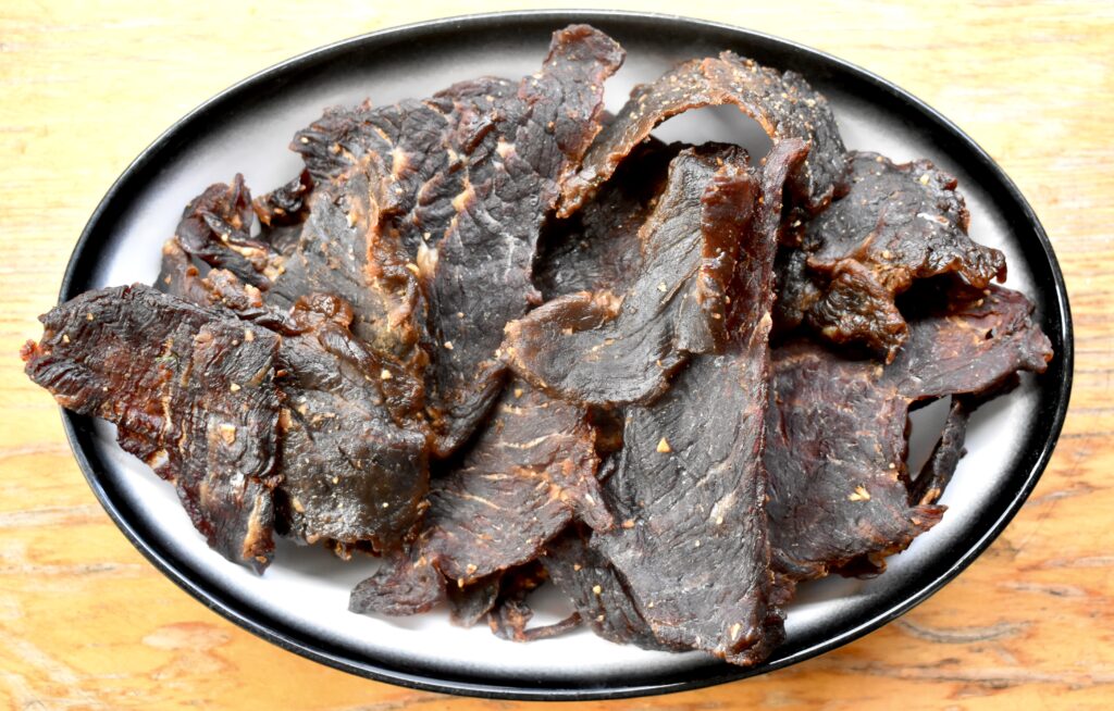 A plate of jerky on a table.