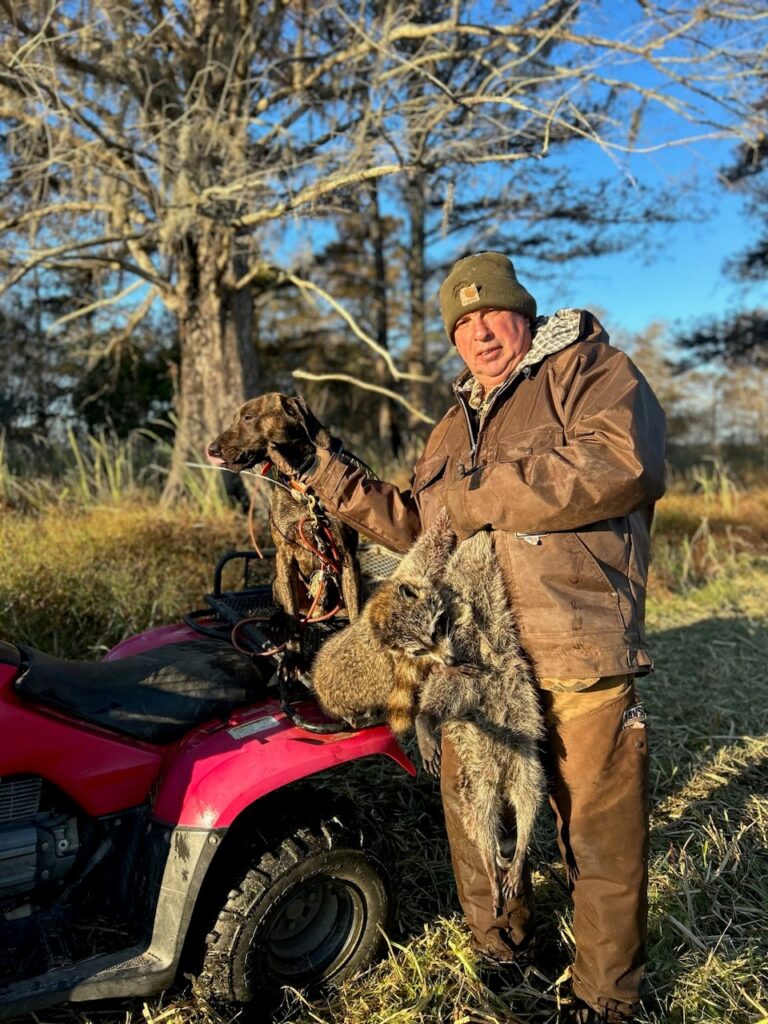 A coon hunter on an ATV with his Plott hound and a few dead raccoons.