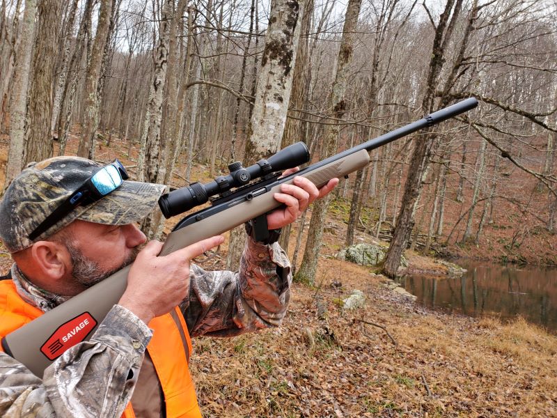 A squirrel hunter shooting a .22 rifle in the woods.