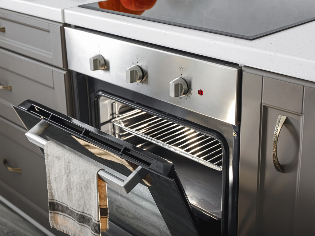 A clean household oven in a kitchen with the oven door open.