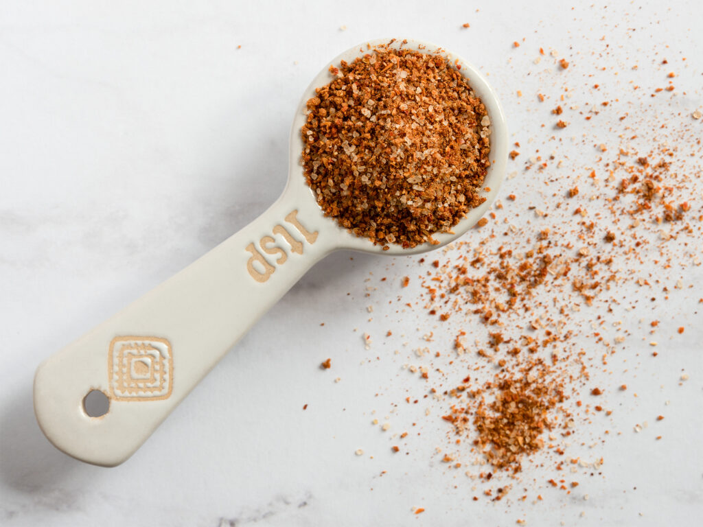 A teaspoon of seasoning on a white background.