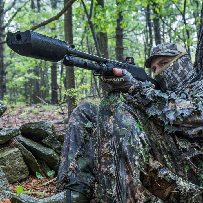 A turkey hunter in camo shooting a shotgun.