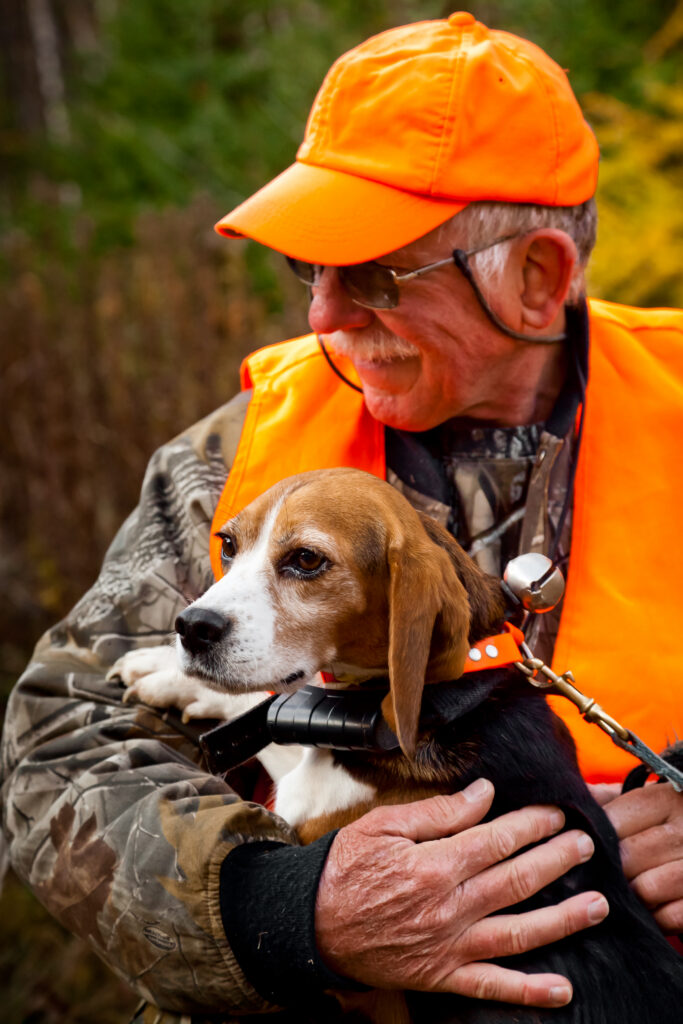 An older male hunter embracing a beagle.