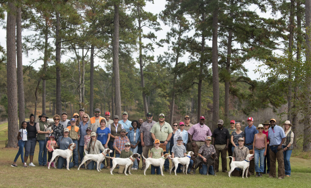 A group of pointing dog field trialers posing for a win photo after an event.