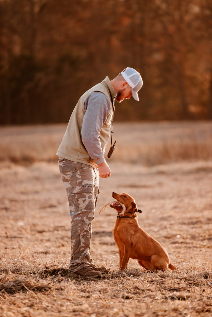 A dog trainer with an English cocker spaniel in the field with a shed antler.