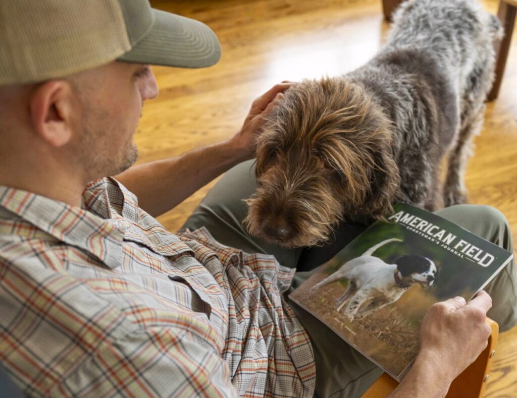 A man and a dog reading a magazine.