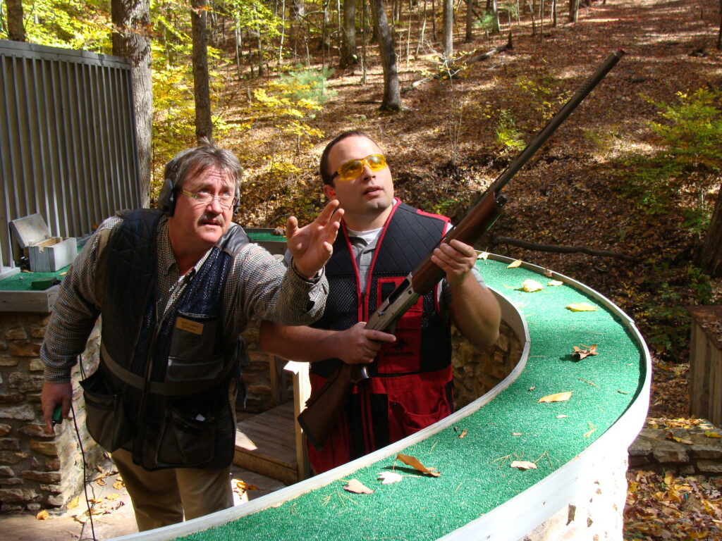 A shooting instructor helps a shotgunner in a round of sporting clays.