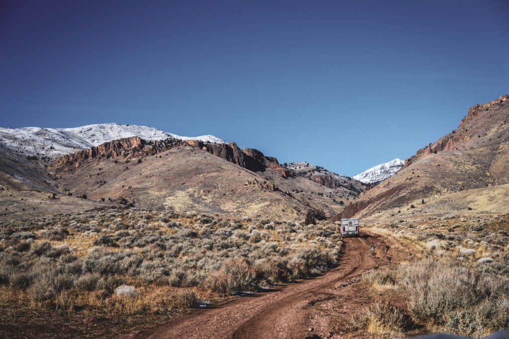 A truck driving down a dirt road in the desert.