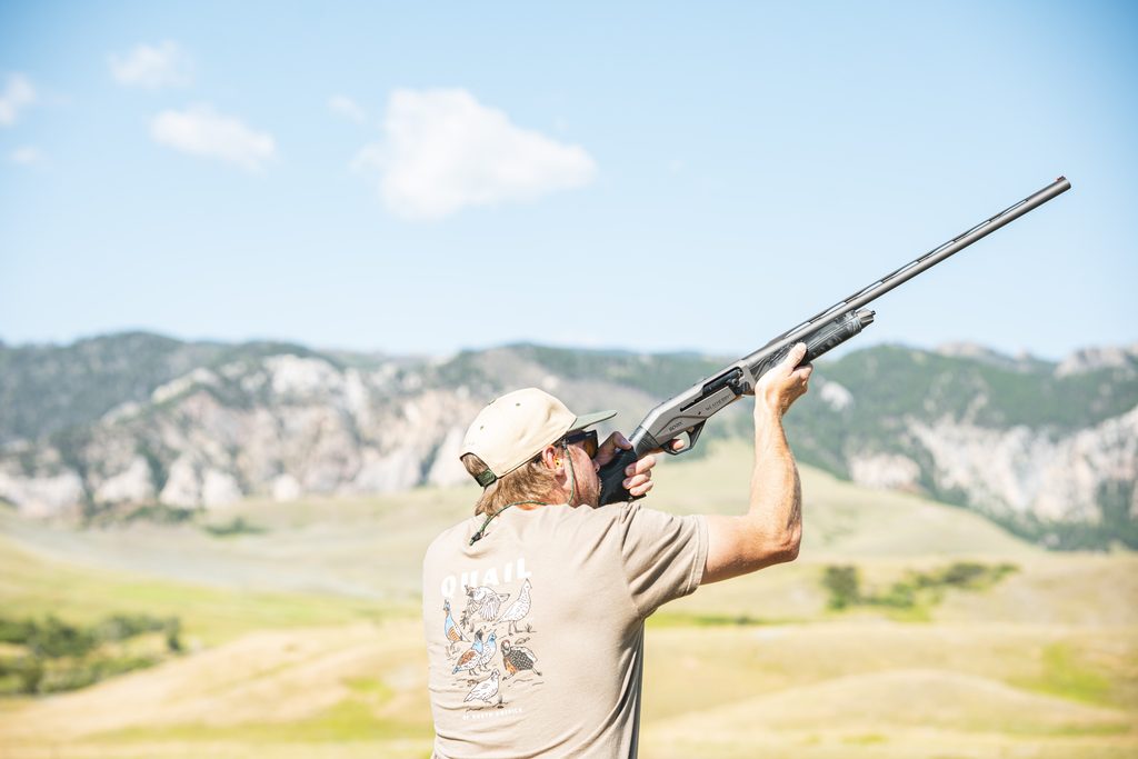 A man shooting a shotgun.