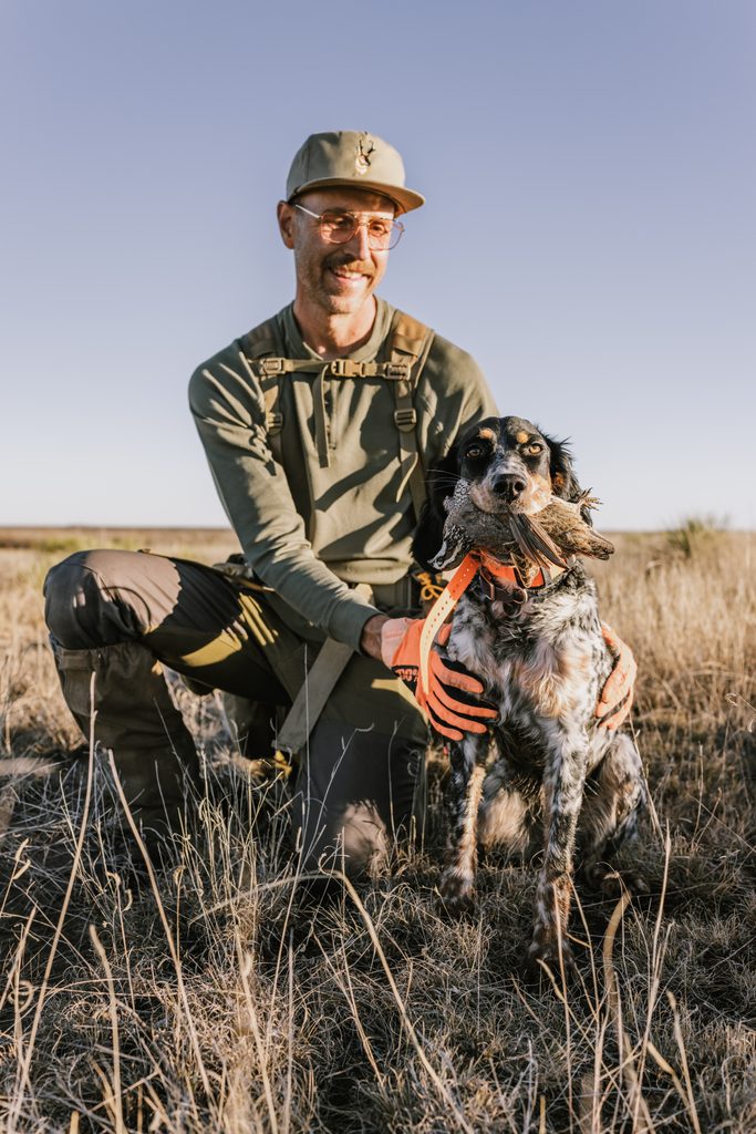A quail hunter with his English setter in a field.